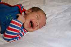 周新生儿婴儿男孩微笑睡觉白色被子