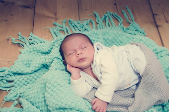 周新生儿婴儿男孩绿色毯子木背景