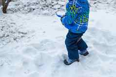 迷人的婴儿男孩挖掘雪蓝色的小铲冬天一天