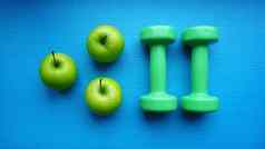 哑铃绿色苹果蓝色的背景健康的生活方式体育运动概念