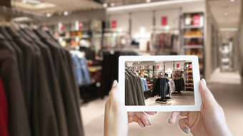 女人手采取平板电脑购物购物中心模糊图像衣服商店