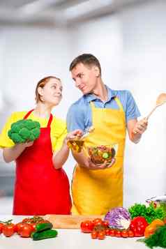 年轻的夫妇爱烹饪vegetab