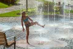 女孩阳光明媚的温暖的一天玩水喷泉女孩幸福的浅清洁水城市喷泉温暖的明亮的夏天一天