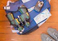 准备旅行旅行背包双筒望远镜相机地图木背景