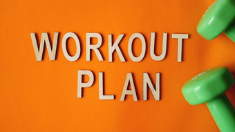 健身概念锻炼计划绿色哑铃橙色背景前视图