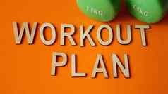 健身概念锻炼计划绿色哑铃橙色背景前视图