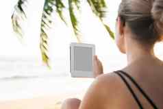 女人持有电子阅读器在户外海棕榈树背景放松享受阅读最喜欢的书户外旅行