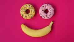 甜甜圈香蕉谎言粉红色的表面形成微笑情感