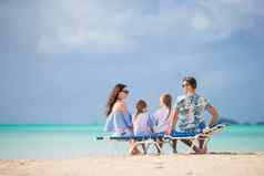 年轻的家庭假期父母孩子们日光浴浴床享受海视图