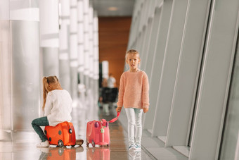可爱的女孩有趣的机场坐着手提箱等待登机