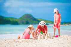家庭使沙子城堡热带白色海滩父亲女孩玩沙子热带海滩