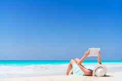 年轻的女人阅读书热带白色海滩