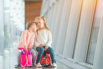 可爱的女孩有趣的机场坐着手提箱等待登机