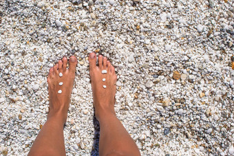 关闭女腿鹅卵石白色桑迪海滩