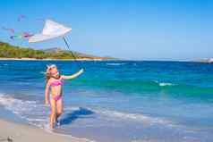 快乐女孩玩飞行风筝热带海滩