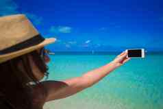 年轻的女人照片电话热带海滩