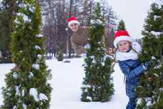 快乐父亲孩子圣诞老人帽子圣诞节树户外