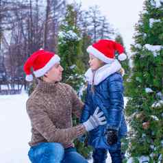 快乐父亲女孩圣诞老人帽子圣诞节树户外