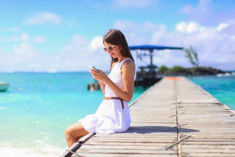 年轻的女人会说话的电话热带海滩假期