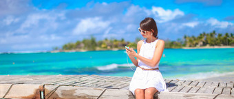 年轻的女人会说话的电话热带海滩假期