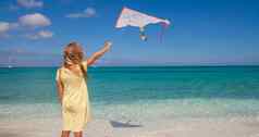快乐女孩玩飞行风筝热带海滩假期