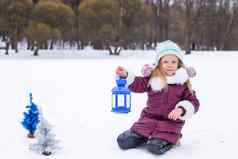 可爱的女孩持有圣诞节灯笼在户外美丽的冬天雪一天