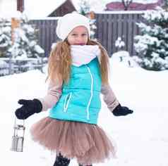 可爱的女孩持有圣诞节灯笼在户外美丽的冬天雪一天
