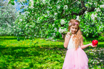 快乐可爱的女孩开花苹果树花园