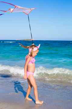 可爱的女孩玩飞行风筝热带海滩假期