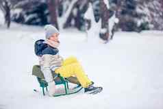 可爱的快乐女孩滑雪橇冬天雪一天