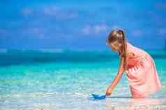 可爱的女孩玩折纸船绿松石海