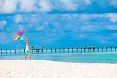 快乐女孩玩飞行风筝热带海滩