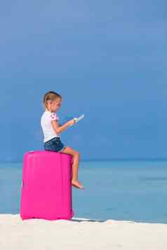 可爱的女孩大粉红色的手提箱地图岛白色海滩