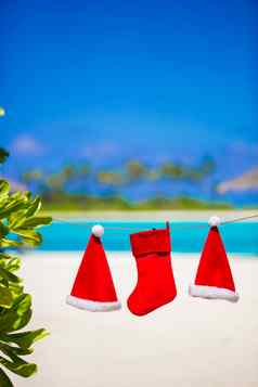 红色的圣诞老人帽子圣诞节长袜挂热带海滩