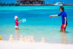 可爱的女孩快乐爸爸玩海滩玩具夏天假期