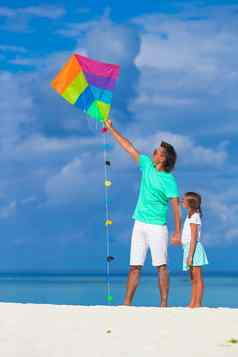 快乐父亲女孩飞行风筝热带海滩