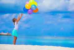 可爱的女孩玩色彩斑斓的气球热带海滩