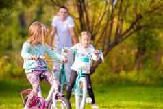 家庭年轻的父亲孩子们骑自行车夏天温暖的一天