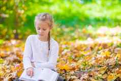 可爱的女孩阅读书美丽的秋天公园