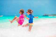 女孩有趣的热带海滩夏天假期玩浅水