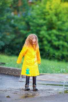 女孩雨衣靴子玩雨在户外
