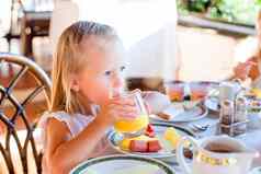 可爱的女孩早餐餐厅可爱的孩子享受新鲜的橙色汁户外咖啡馆