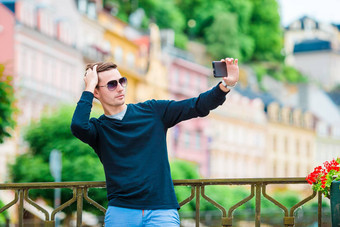 旅游男人。采取旅行照片智能手机夏天假期年轻的有吸引力的旅游采取自拍照片移动电话在户外享受假期旅行目的地旅游探索概念
