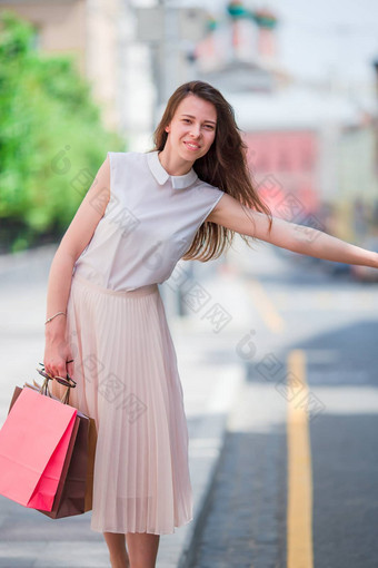 年轻的快乐女孩购物袋抓出租车肖像美丽的快乐女人站街持有购物袋微笑捕捉出租车