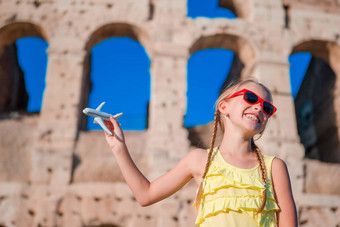 可爱的女孩小玩具模型飞机背景罗马圆形大剧场罗马意大利