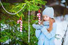 肖像可爱的微笑女孩蓝色的外套连指手套站装饰圣诞节树冷淡的冬天一天户外