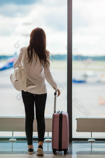 年轻的女人大全景窗口机场休息室等待到达