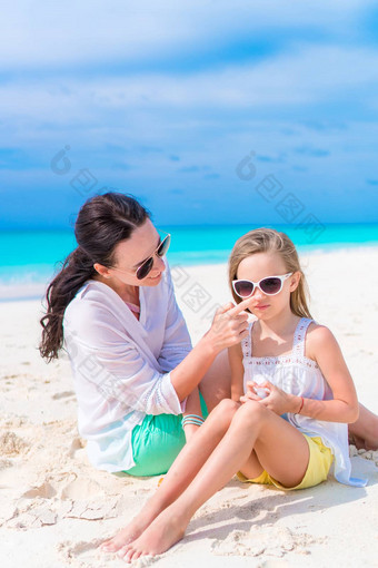 有爱心的妈妈。应用太阳奶油女儿鼻子海滩概念保护紫外线辐射