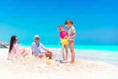 家庭孩子们使沙子城堡热带海滩