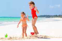 可爱的女孩夏天假期孩子们玩海滩玩具白色海滩